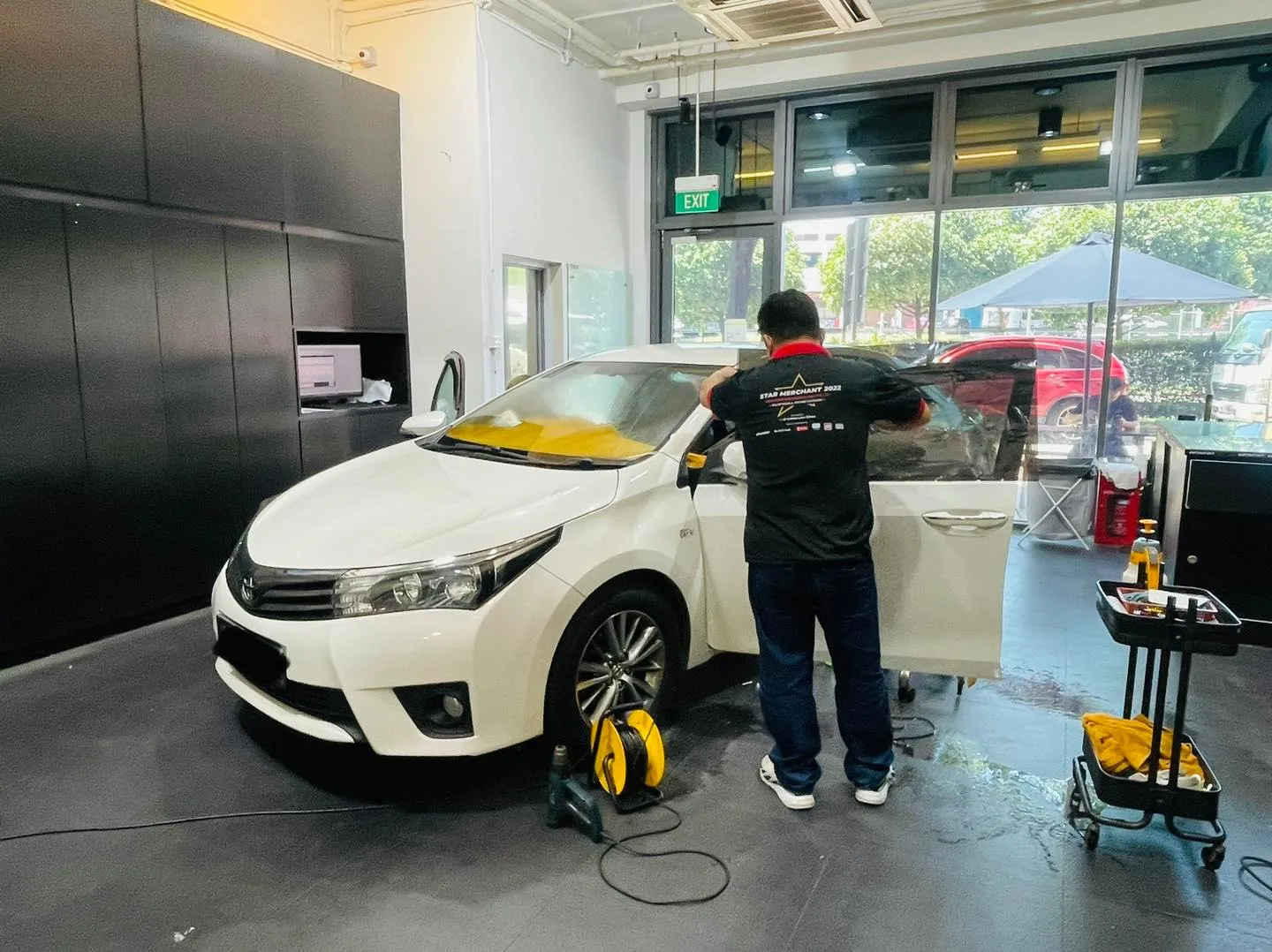 Installer applying window film to a white Toyota Altis at Infratint Singapore