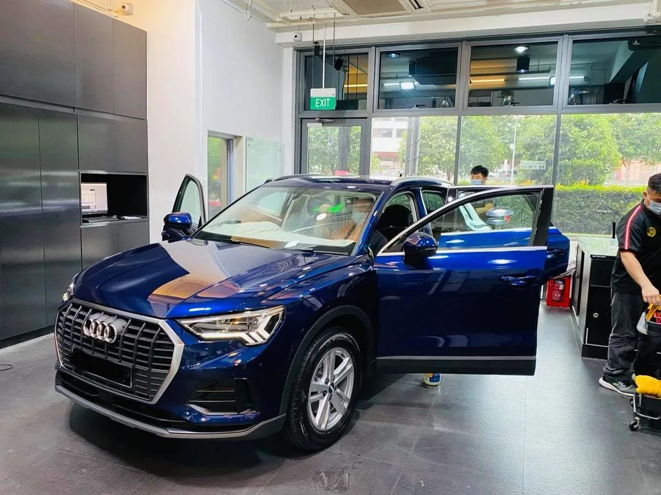 Blue Audi Q3 in front three-quarter view during window film installation at Infratint Singapore