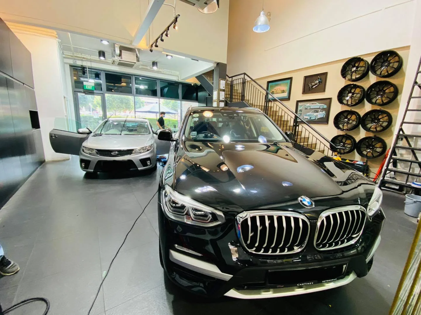 Black BMW SUV at Infratint Singapore beside a silver Kia and a wheel display