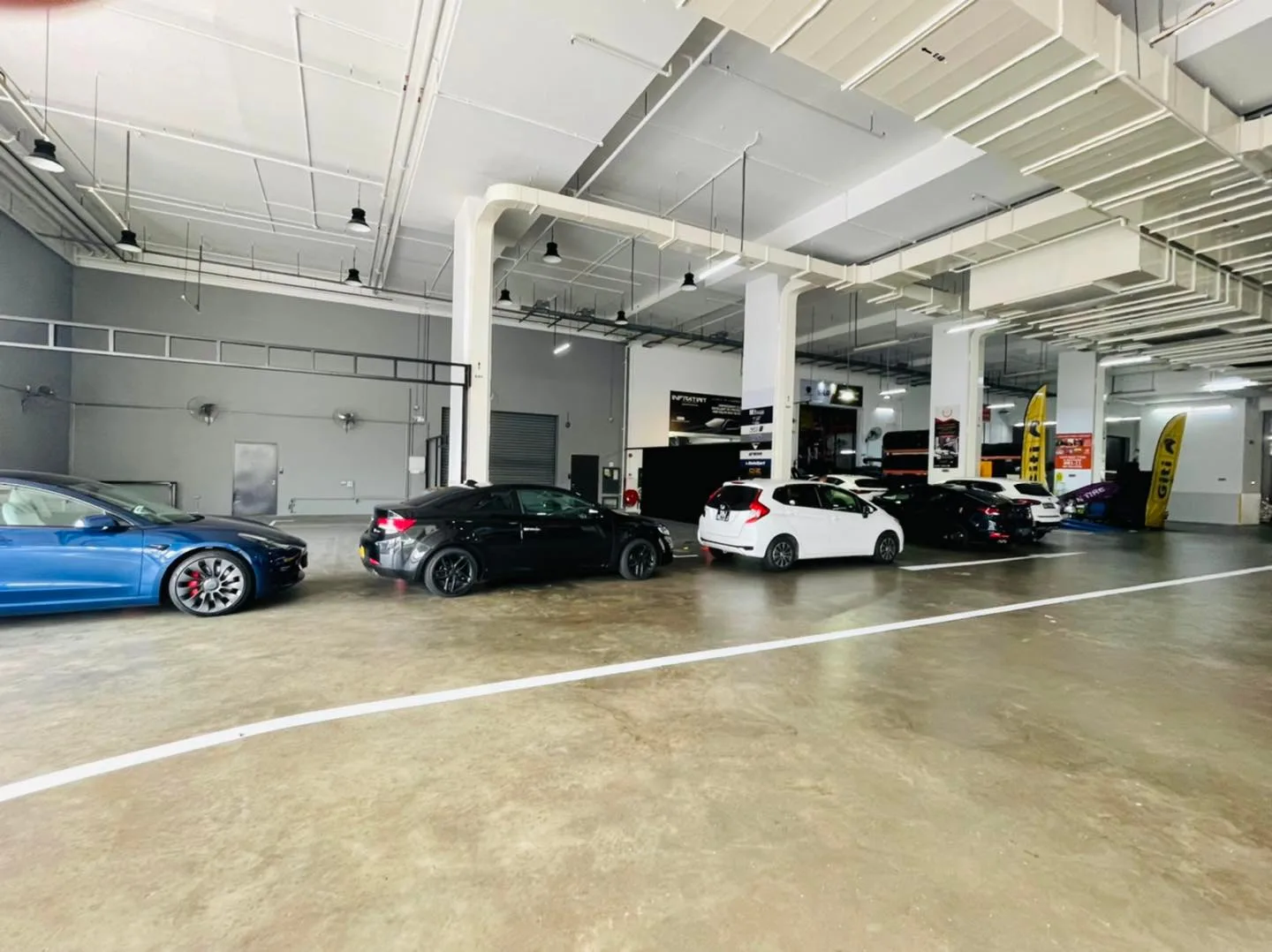 Blue Tesla Model 3 and several other cars inside the Infratint Singapore workshop