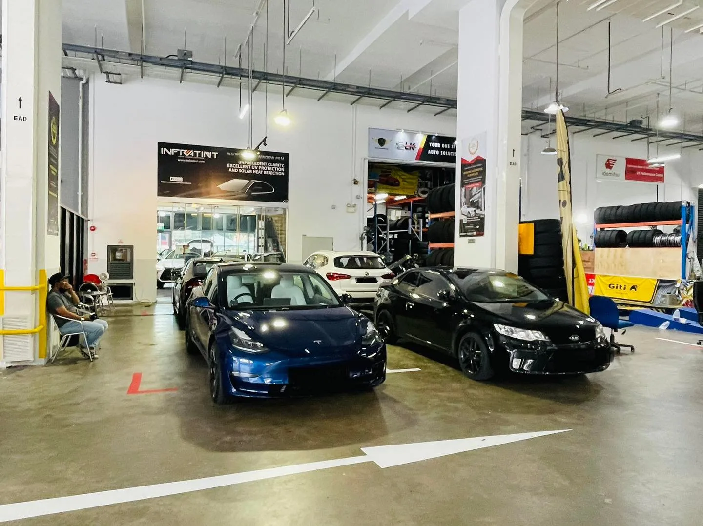 Blue Tesla Model 3 and a black coupe inside the Infratint Singapore workshop