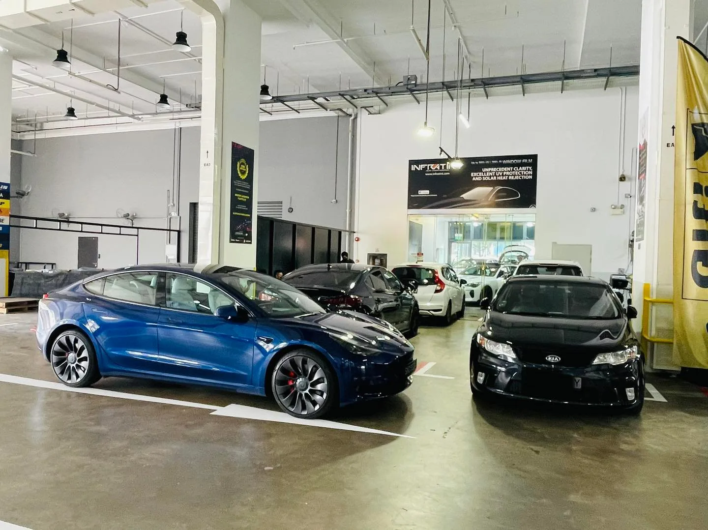 Blue Tesla Model 3 and a black sedan at the Infratint Singapore workshop