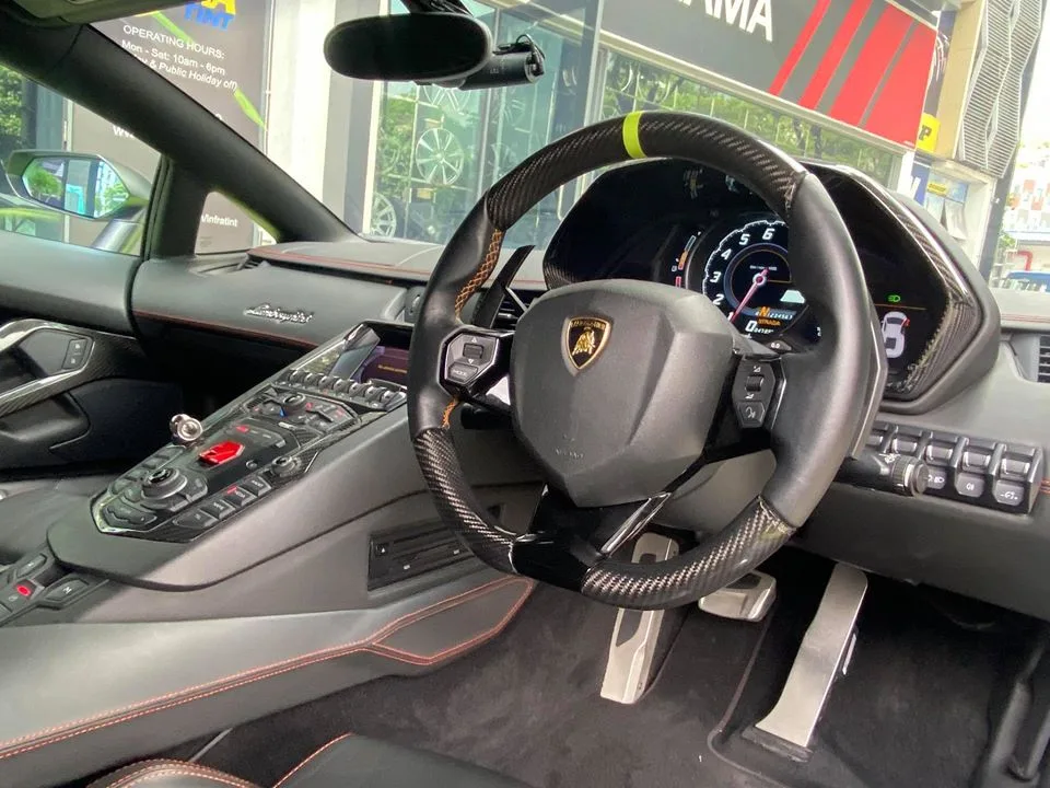 Carbon fibre steering wheel and dashboard inside a Lamborghini Aventador tinted at Infratint Singapore