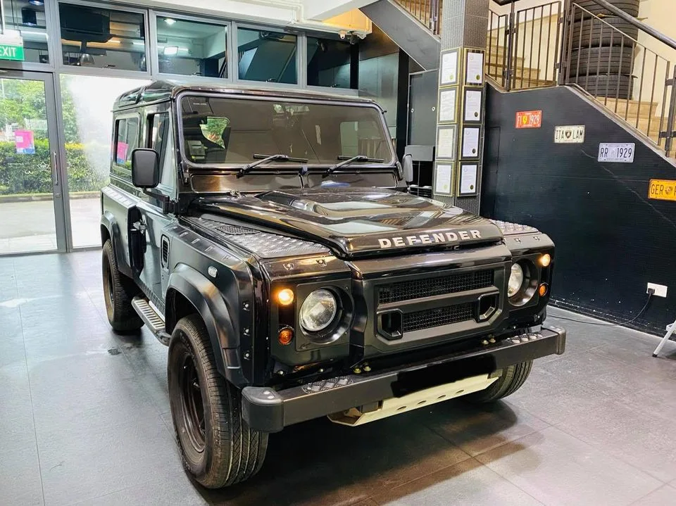 Black Land Rover Defender front view with headlights on at Infratint Singapore