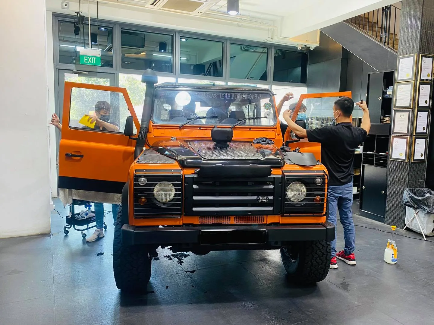 Orange Land Rover Defender with doors open during window tinting at Infratint Singapore