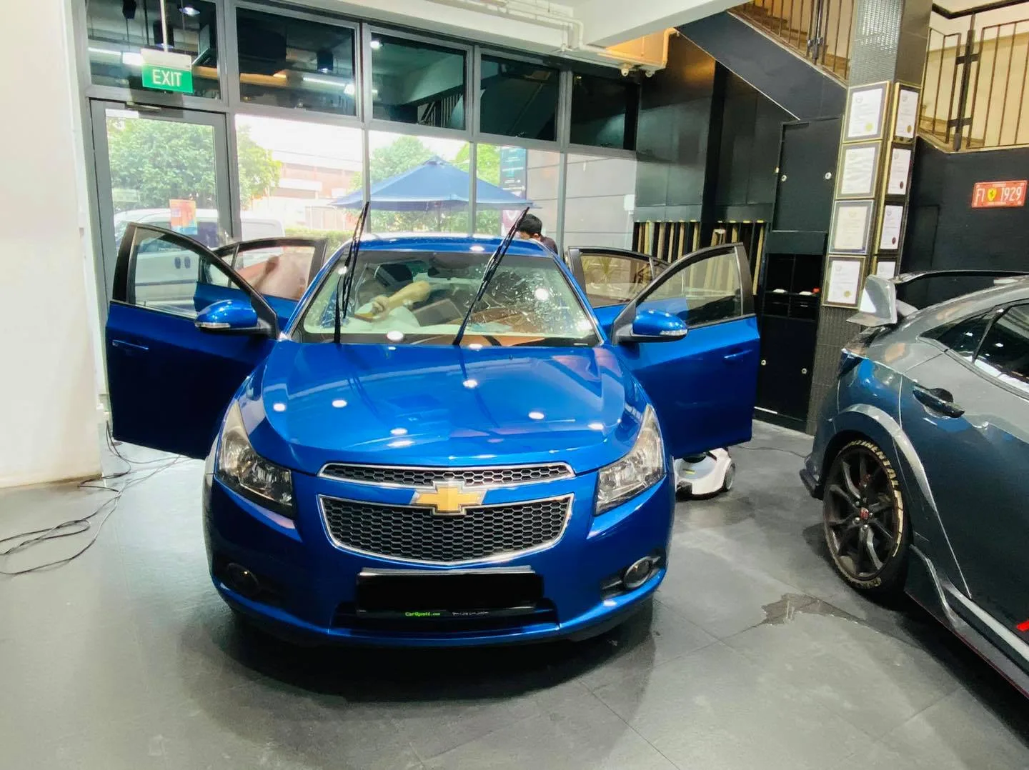 Blue Chevrolet Cruze with doors open during window tinting at Infratint Singapore
