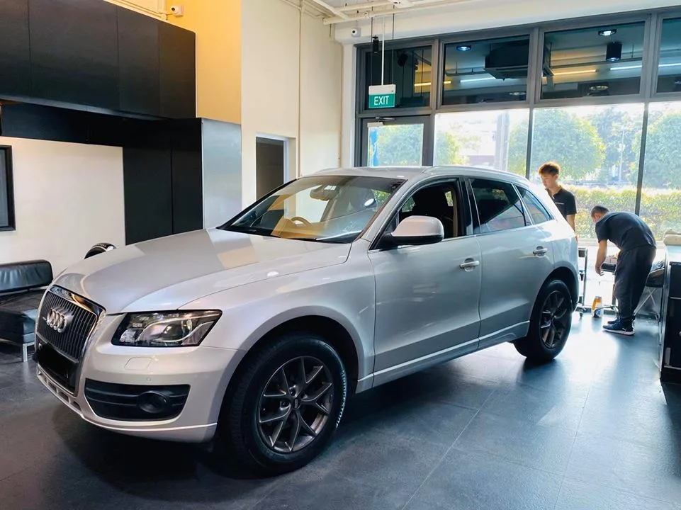 Technicians tinting the side windows of a silver Audi Q5 at Infratint Singapore