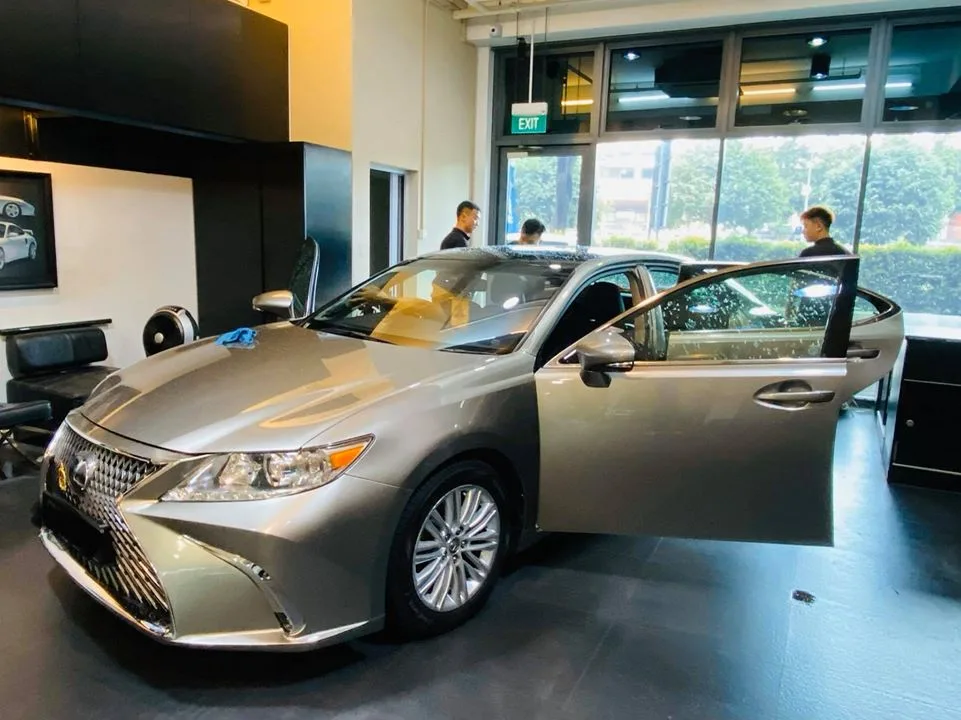 Front three-quarter of a champagne Lexus ES sedan with doors open at Infratint Singapore
