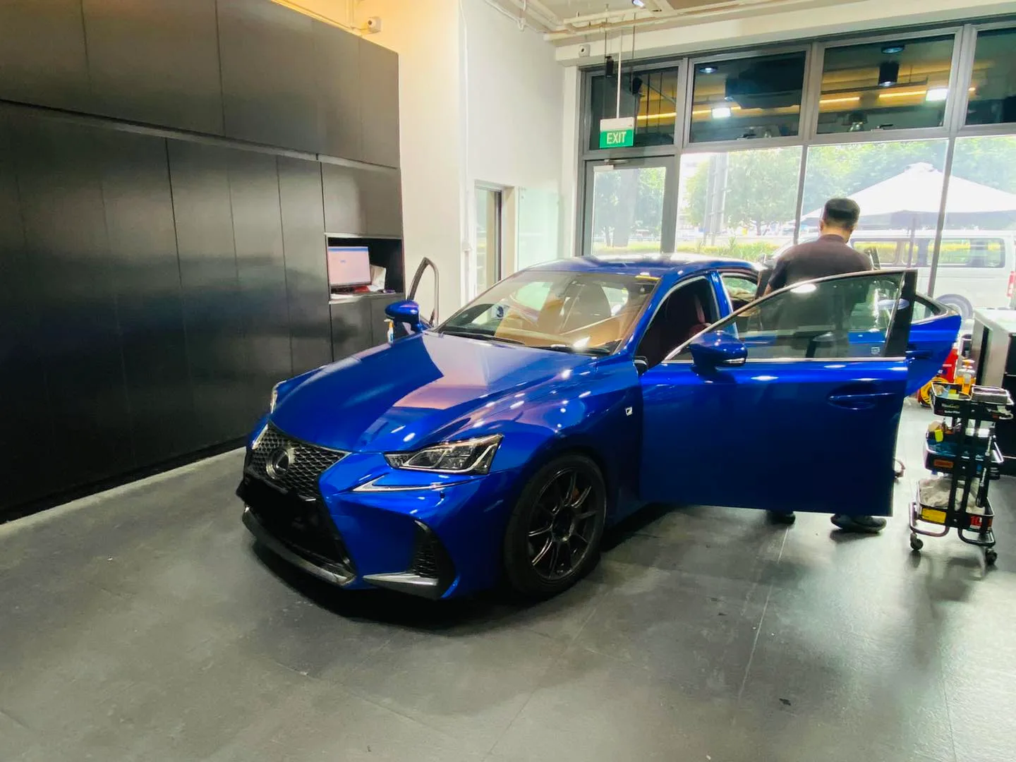 Blue Lexus IS front three-quarter view during window film install at Infratint Singapore