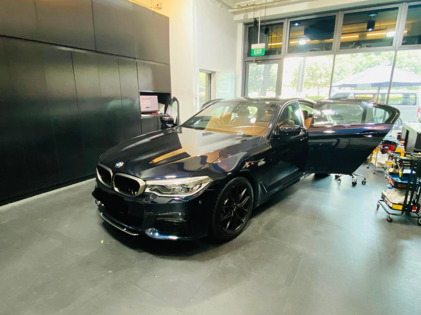 Dark blue BMW 5 Series front three-quarter view during window film install at Infratint Singapore