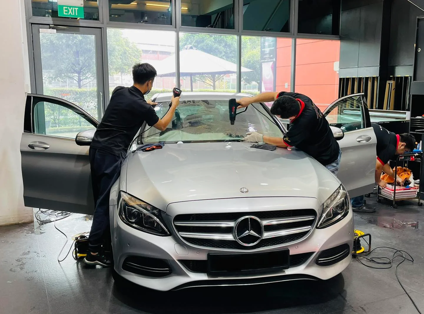 Silver Mercedes-Benz sedan windscreen being tinted by two installers at Infratint Singapore