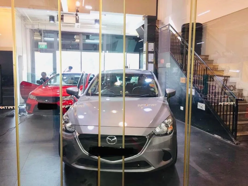 Silver Mazda hatch and a red coupe with scissor doors during window tinting at Infratint Singapore