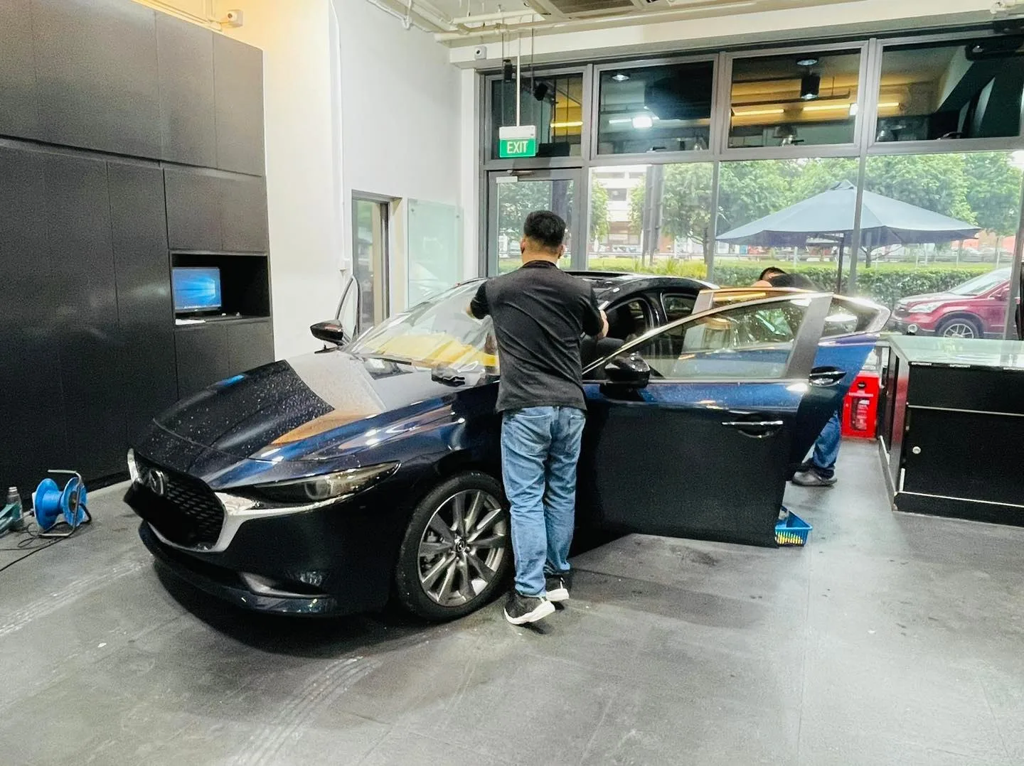 Side view of a dark blue Mazda 3 during window tinting at Infratint Singapore