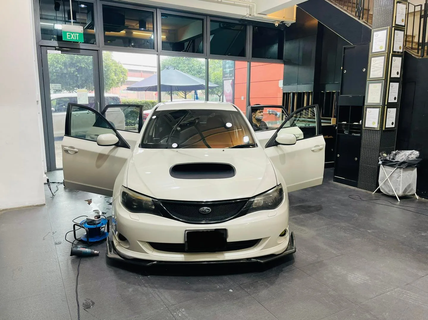 White Subaru Impreza with hood scoop being prepped for window film at Infratint Singapore