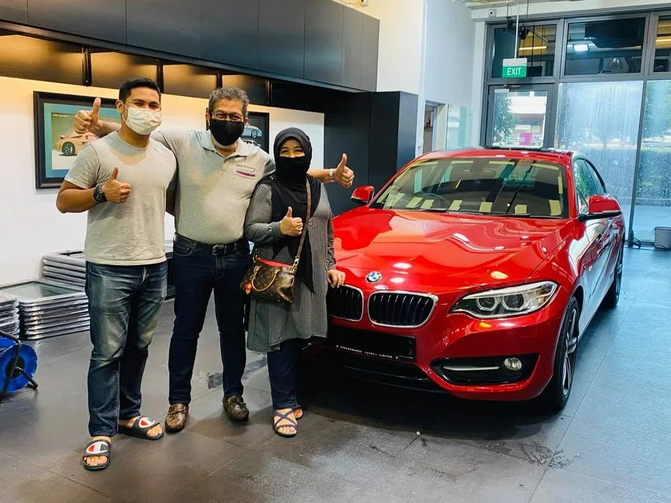 Three people giving a thumbs-up next to a red BMW 2 Series coupe at Infratint Singapore