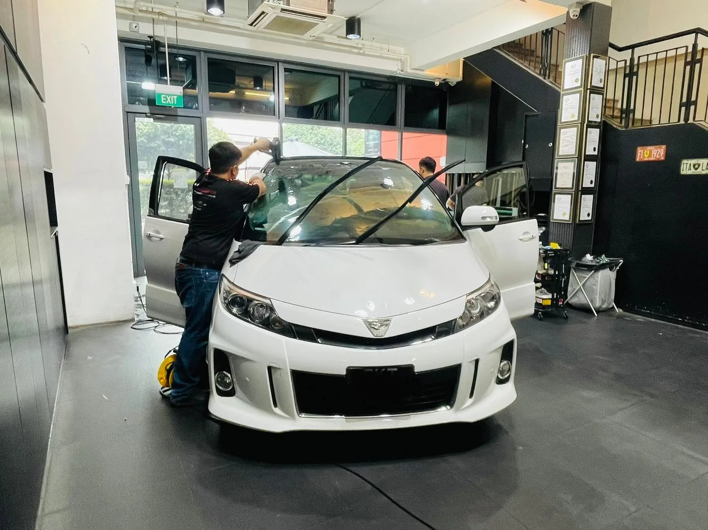 Installer applying window film to a white Toyota Estima at Infratint Singapore