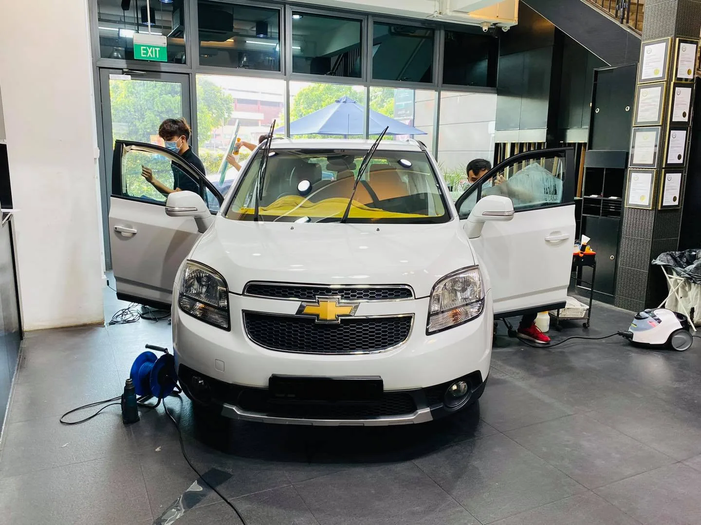 White Chevrolet Orlando MPV having its windows tinted by technicians at Infratint Singapore