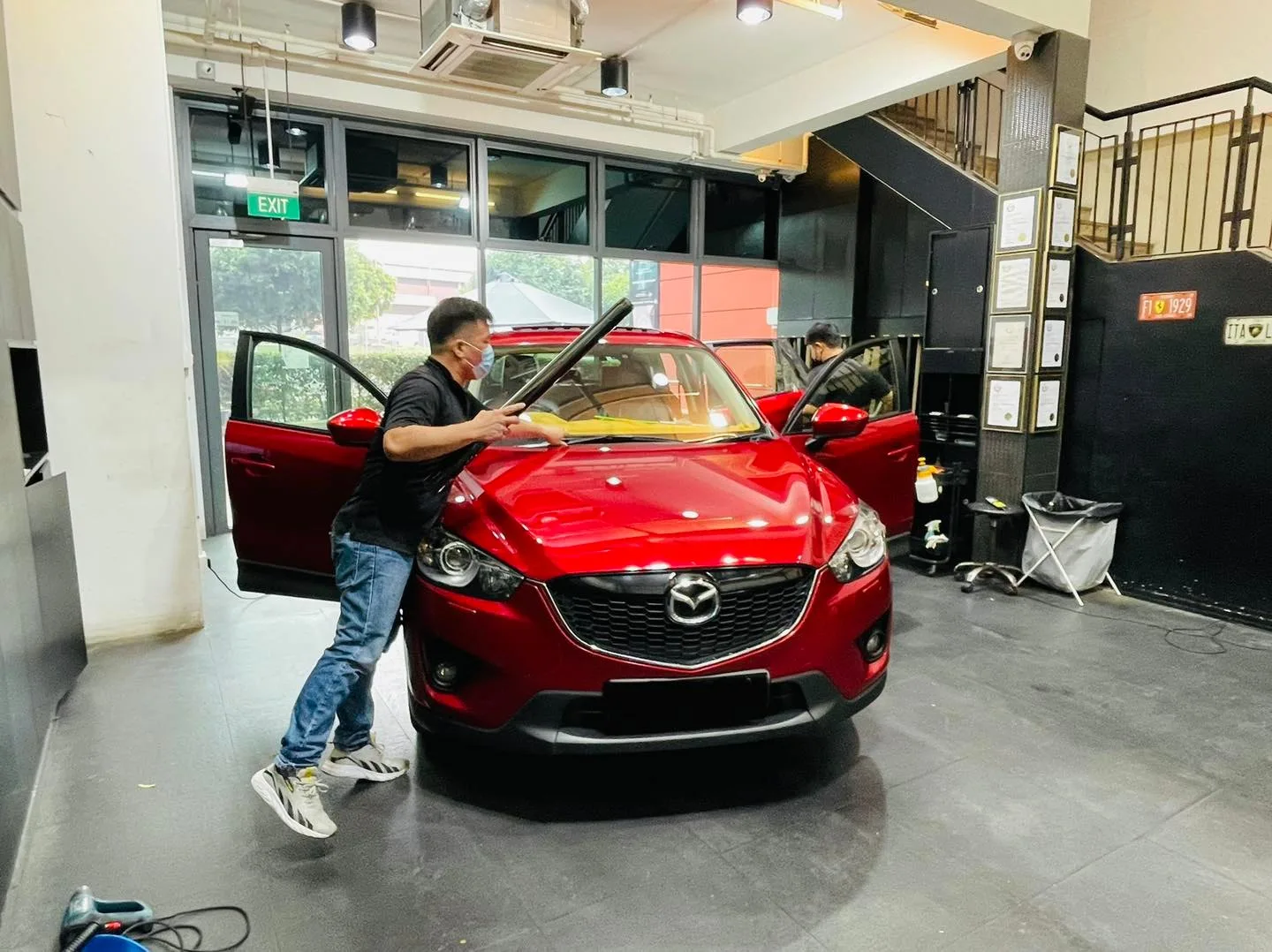 Installer applying window film to the windscreen of a red Mazda CX-5 at Infratint Singapore
