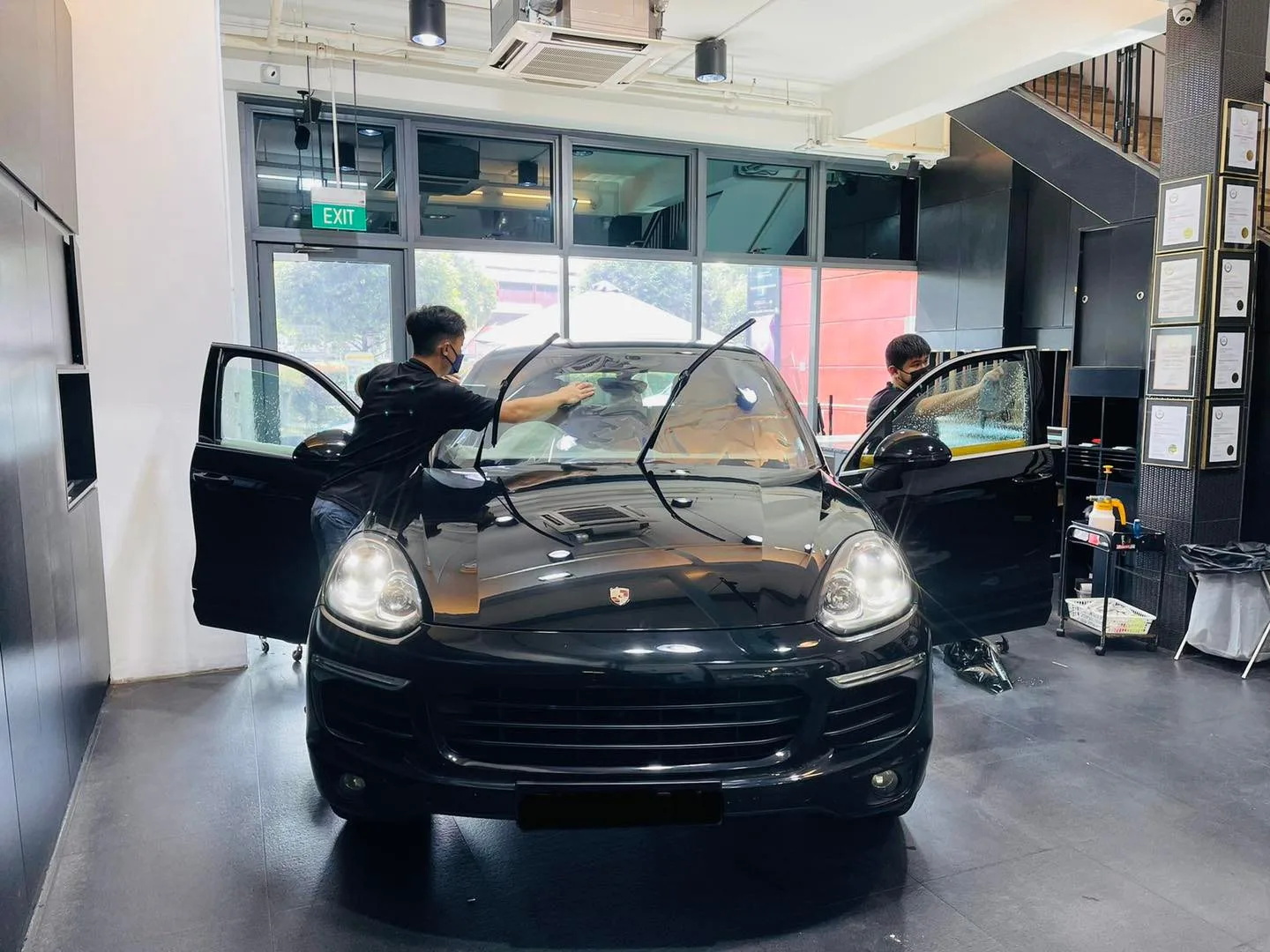 Black Porsche Cayenne with installers fitting window film at Infratint Singapore