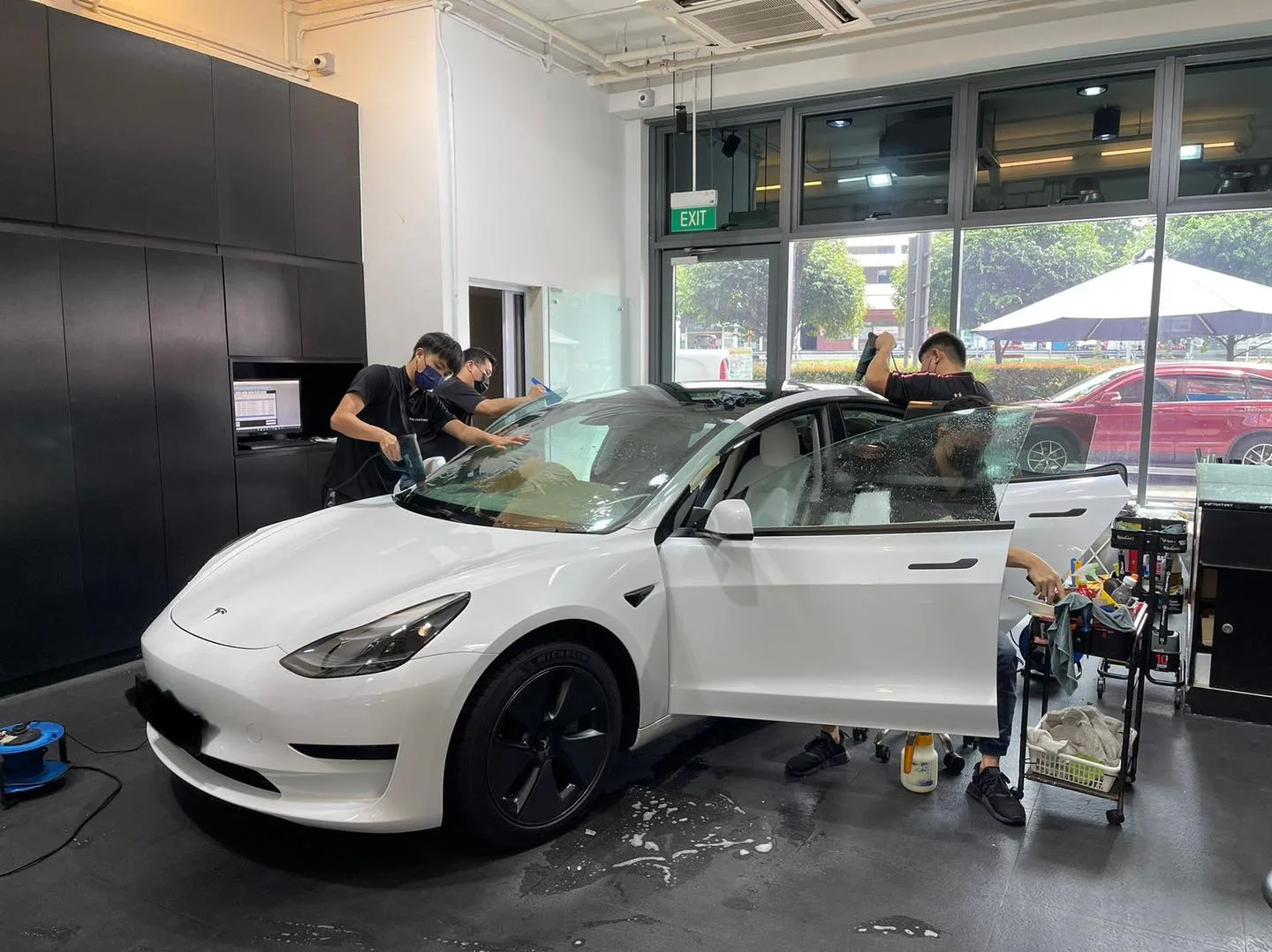White Tesla Model 3 in three-quarter view during window tinting at Infratint Singapore