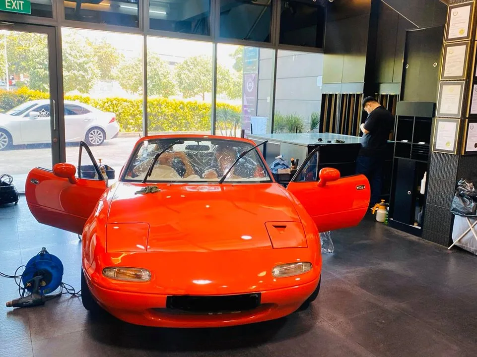 Red Mazda MX-5 roadster with pop-up headlights inside Infratint Singapore for window tinting