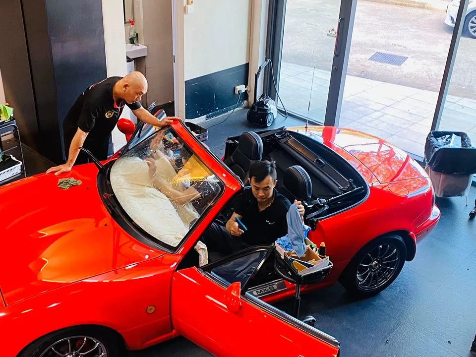 Installers tinting a red Mazda MX-5 roadster with the roof removed at Infratint Singapore