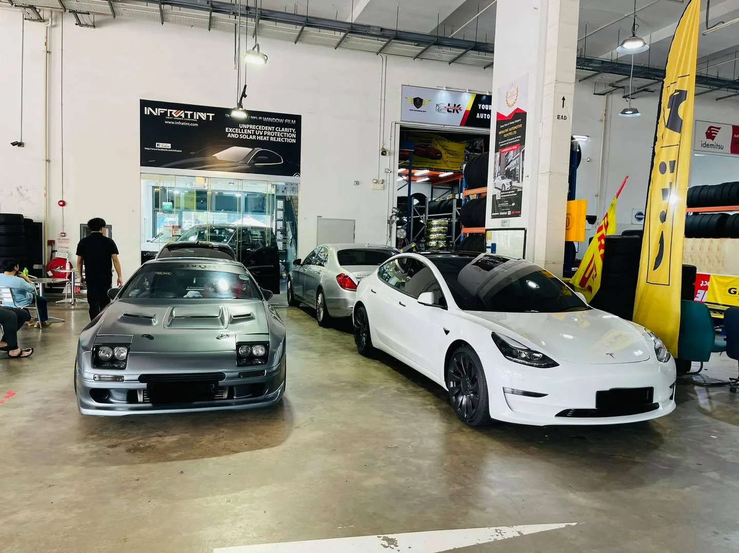 Silver Mazda RX7 FC3S and white Tesla Model 3 inside the Infratint Singapore workshop