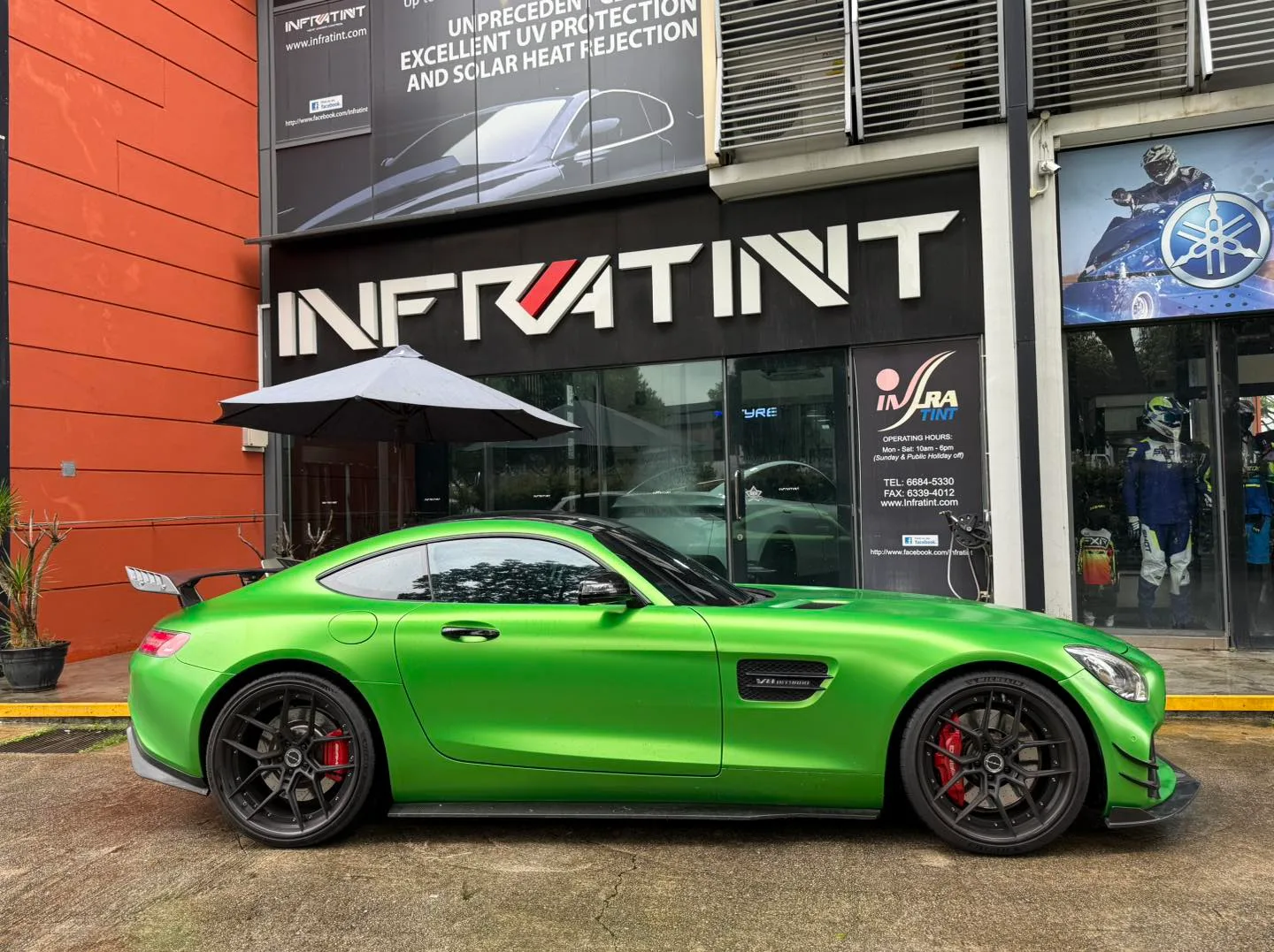 Green Mercedes-AMG GT side profile with rear wing and tinted glass outside Infratint Singapore