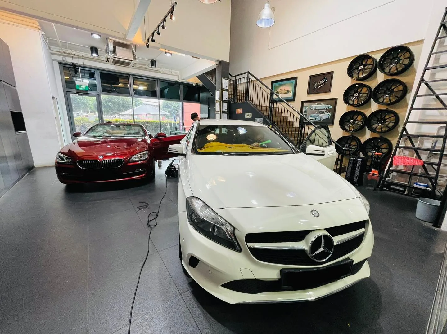 White Mercedes-Benz sedan and red BMW convertible inside the Infratint Singapore install bay
