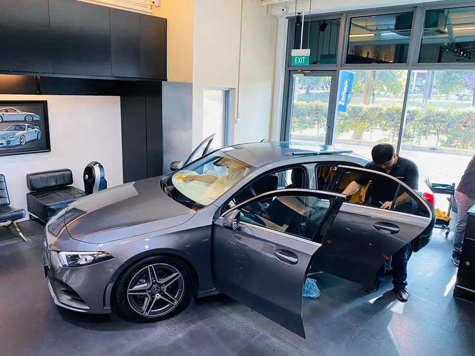 Technician tinting the rear door of a grey Mercedes-Benz A-Class at Infratint Singapore