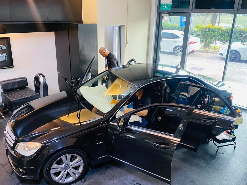 Technician applying window film inside a black Mercedes-Benz C-Class at Infratint Singapore