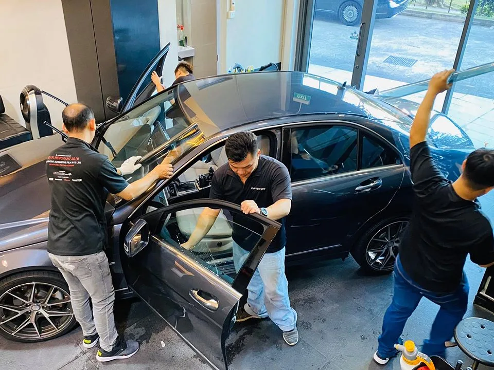 Overhead view of technicians installing window film on a grey Mercedes-Benz sedan at Infratint Singapore