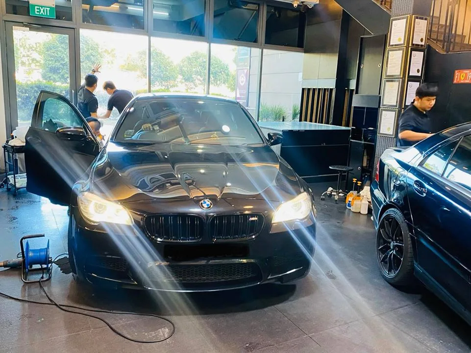 Black BMW M5 with door open during window tinting at Infratint Singapore