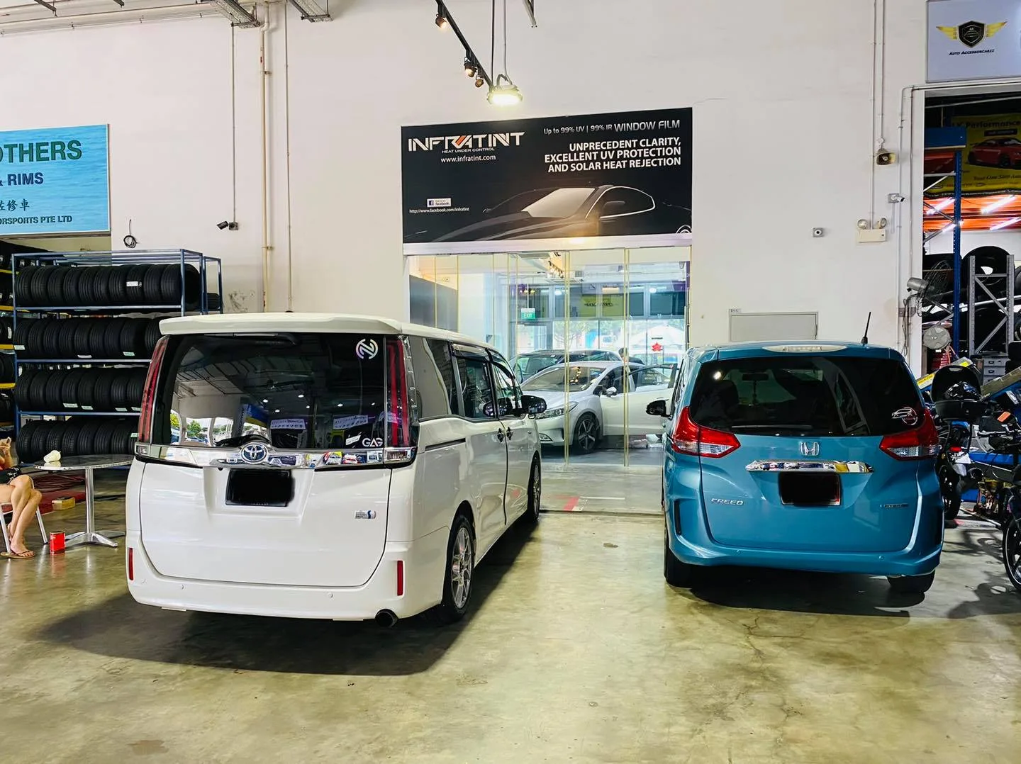 White Toyota van and blue Honda awaiting window film at Infratint Singapore