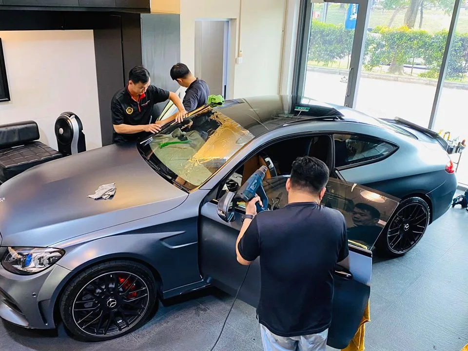 Installers fitting window film to a matte grey Mercedes-Benz C-Class coupe at Infratint Singapore