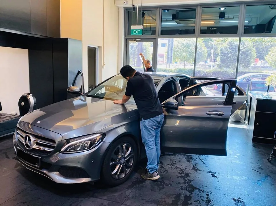 Installer fitting window film to a grey Mercedes-Benz C-Class at Infratint Singapore