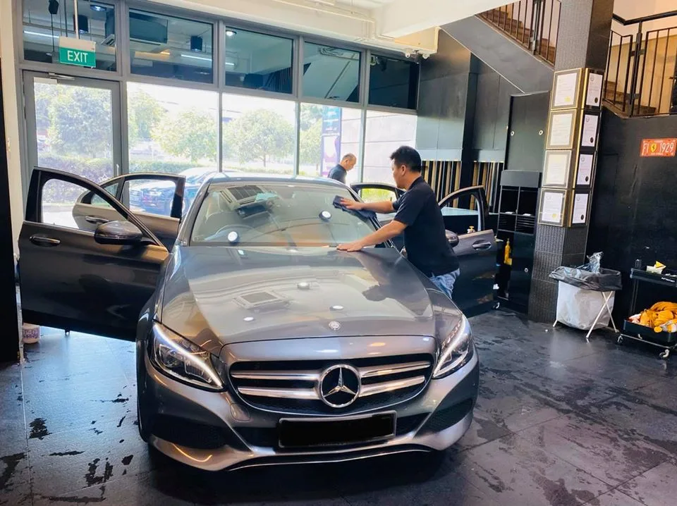 Technician applying windscreen film to a grey Mercedes-Benz C-Class at Infratint Singapore