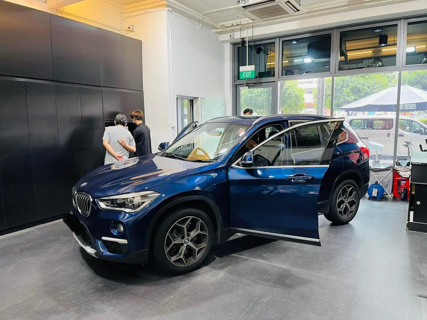 Blue BMW X1 having its windows tinted by two installers at Infratint Singapore