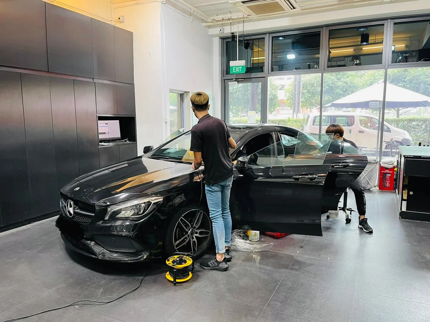 Black Mercedes-Benz CLA having its side windows tinted by two installers at Infratint Singapore