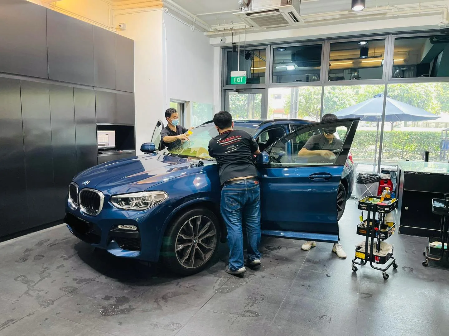 Installers tinting a blue BMW X3 SUV at Infratint Singapore