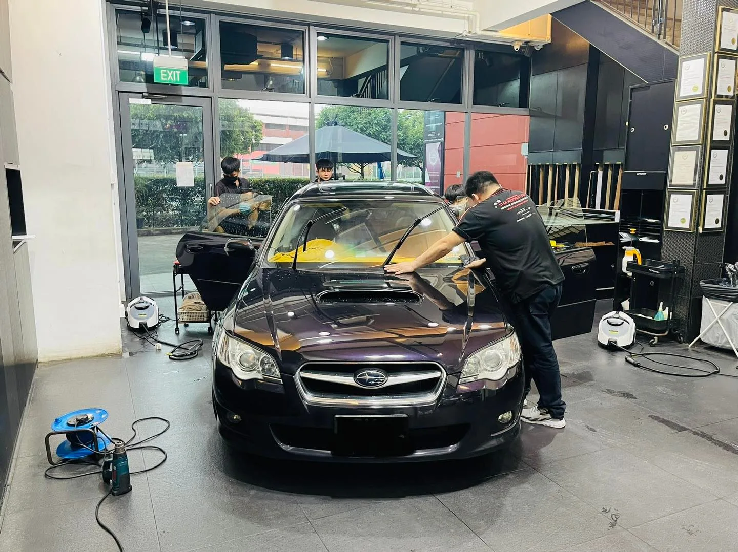 Installer tinting a dark Subaru Legacy at Infratint Singapore