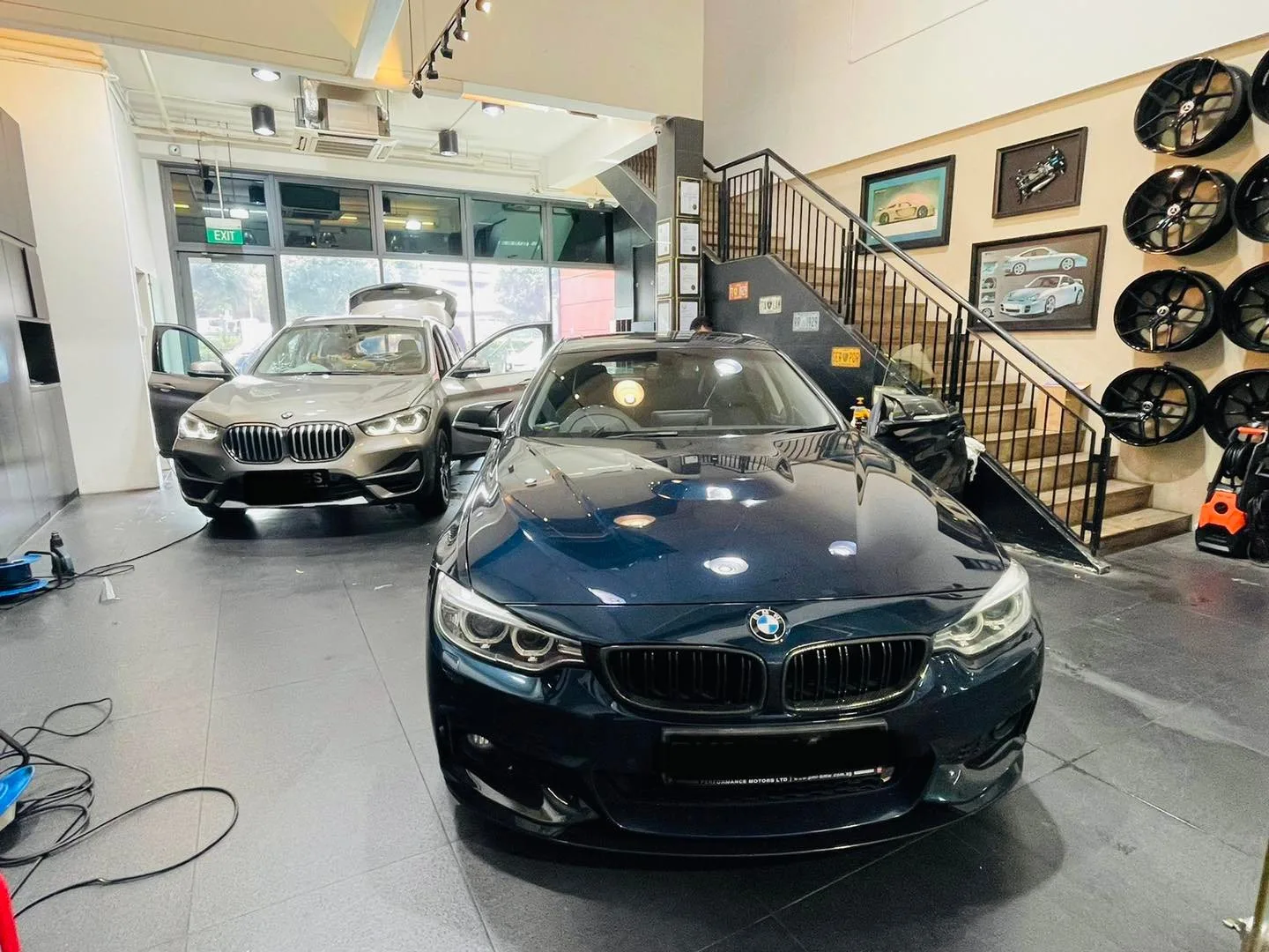 Blue BMW coupe and grey BMW sedan in the Infratint Singapore workshop for tinting