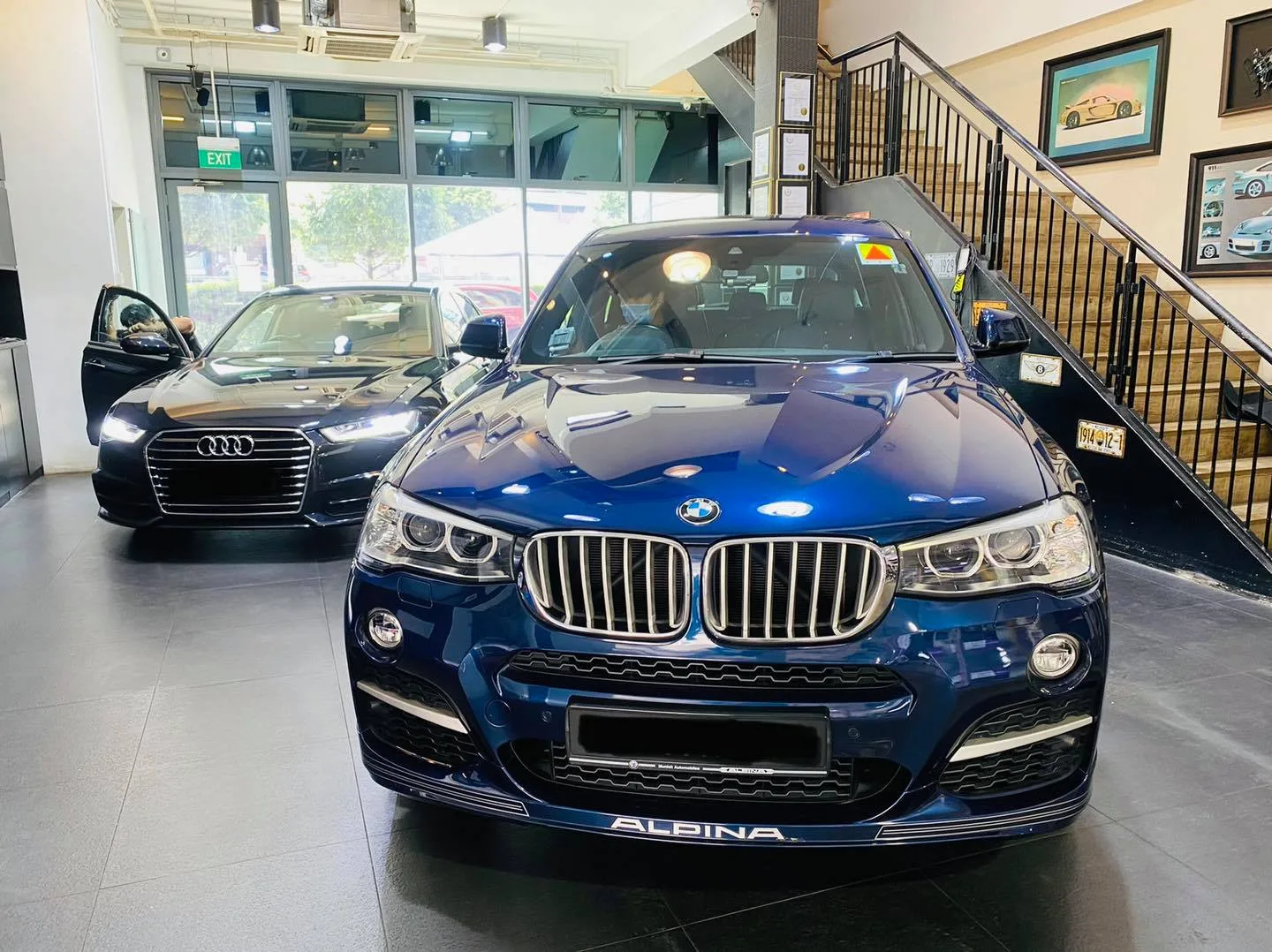 Blue BMW Alpina SUV and dark Audi sedan inside the Infratint Singapore showroom