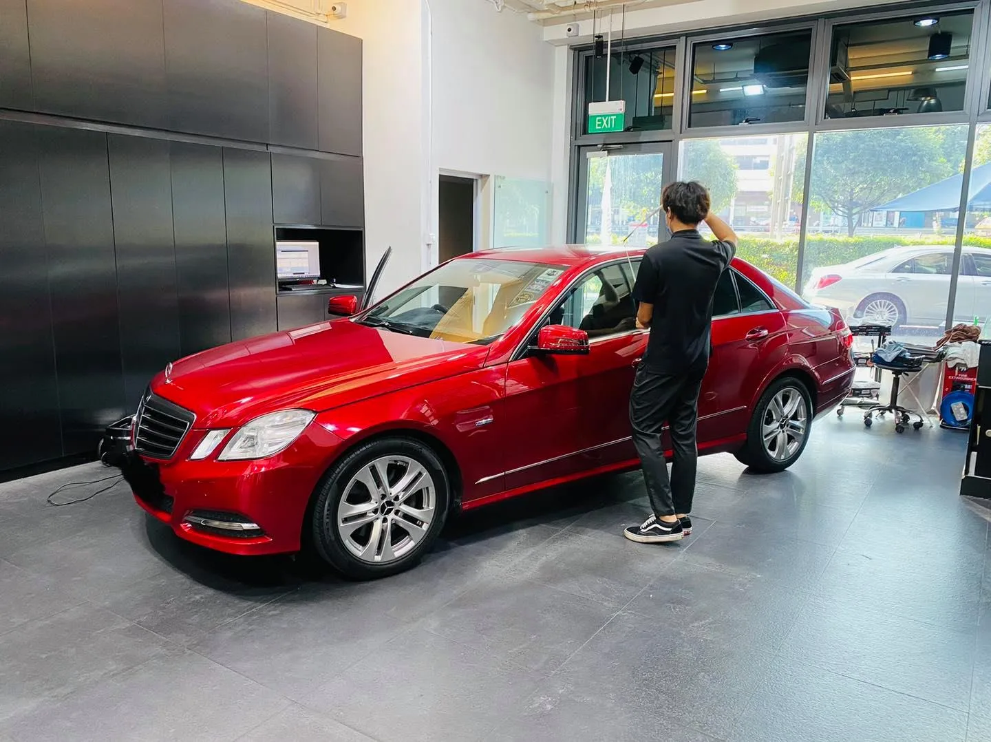 Installer tinting the side glass of a red Mercedes-Benz E-Class at Infratint Singapore
