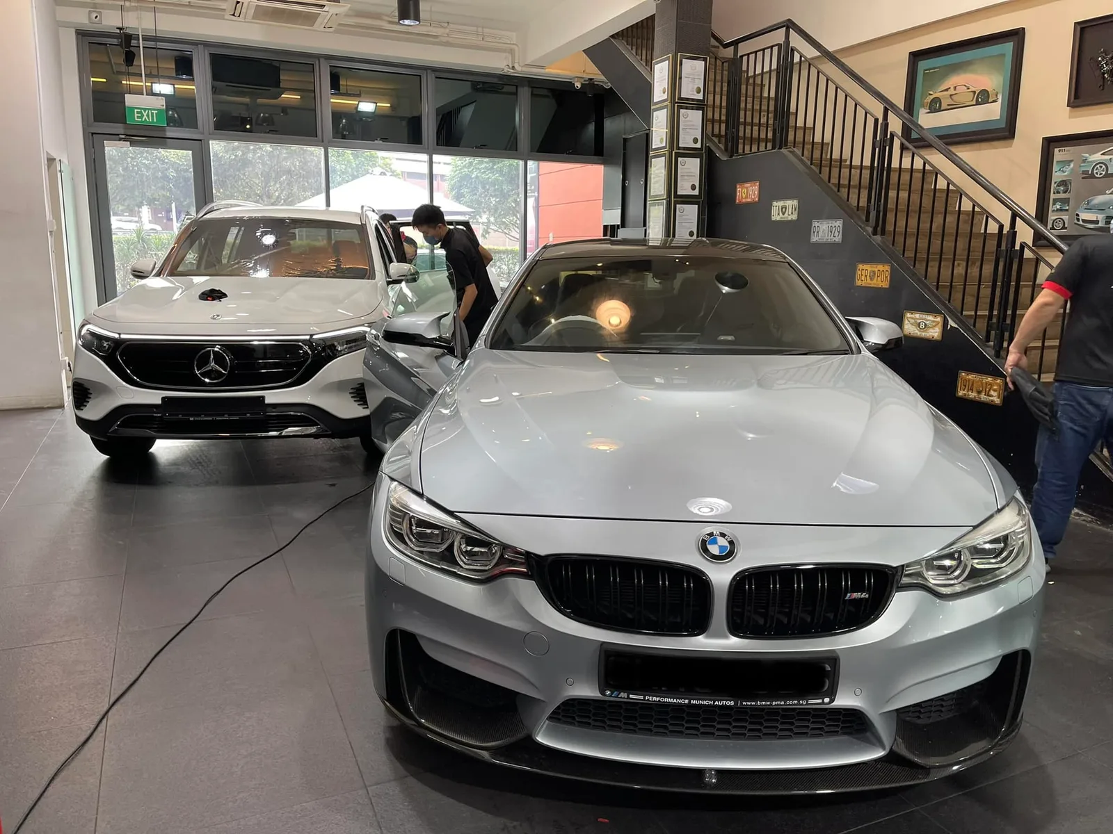 Silver BMW M sedan and white Mercedes-Benz EQB inside the Infratint Singapore showroom