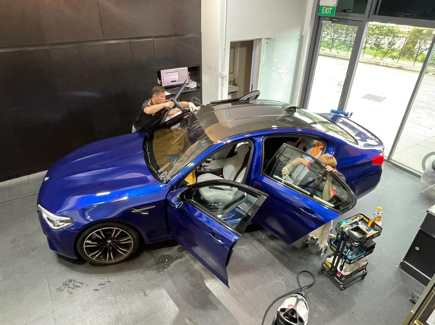 Overhead rear quarter of a blue BMW M-Sport sedan being tinted at Infratint Singapore