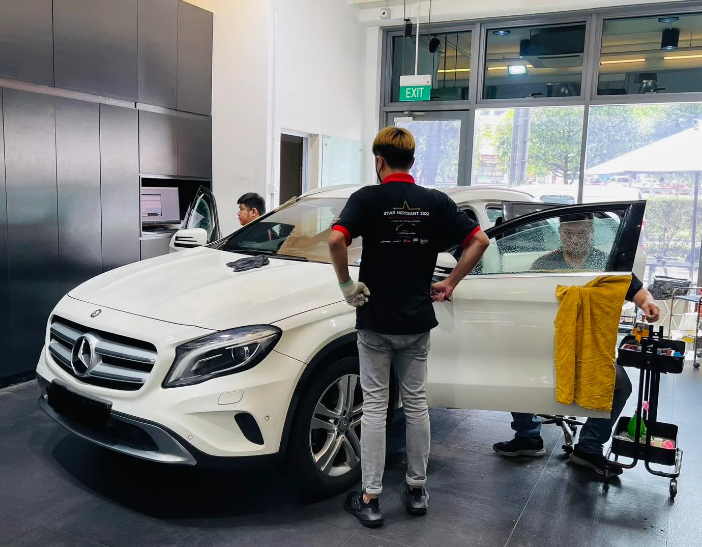 Installer tinting a white Mercedes-Benz GLA from the front three-quarter view at Infratint Singapore