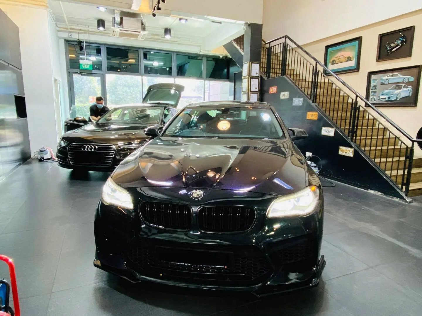 Black BMW sedan and brown Audi inside Infratint Singapore for window tinting