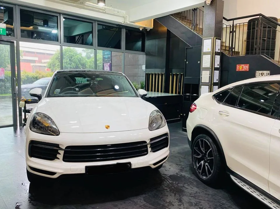 White Porsche Cayenne and white Mercedes-Benz GLC coupe inside the Infratint Singapore showroom