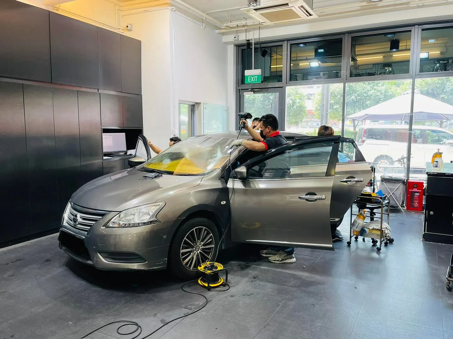 Installer applying window film to a grey Nissan Sylphy at Infratint Singapore